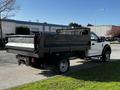 A 2018 Ford F-550 with a flatbed and open back is parked on the street, showcasing its utility design and robust build