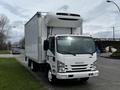 A white 2018 Isuzu NRR box truck with a refrigerated unit on top parked on a roadway