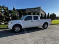 A white 2015 Nissan Frontier is parked on the street featuring a crew cab design and alloy wheels