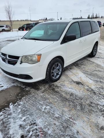 A white 2012 Dodge Grand Caravan parked on a snowy surface with a clean exterior and alloy wheels