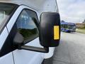 A 2020 Chevrolet Express van with a side mirror featuring a yellow indicator strip