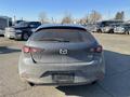 A 2023 Mazda MAZDA3 hatchback with a dusty exterior parked at a lot viewed from the rear showing its taillights and logo