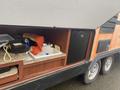 A 2015 Winnebago of Indiana Travel Trailer showing an outdoor kitchenette area with a sink, counter space, and a small refrigerator