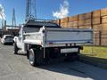 A 2008 Ford F-450 SD with a gray and white exterior featuring a flatbed truck design and large rear tires parked on a street