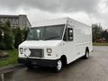 A 2011 Ford Econoline cargo van with a plain white exterior and a boxy shape positioned at an angle with its front facing forward