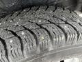 Close-up of a rugged tire showcasing deep tread patterns and visible metal studs for enhanced traction on various surfaces