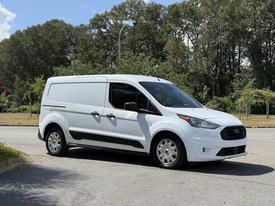 A white 2021 Ford Transit Connect van parked with its side facing the viewer showcasing its sleek design and spacious cargo area
