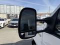 A 2023 Ford E-450 side mirror reflecting an image of the surroundings
