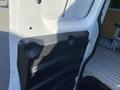 Interior view of a 2012 GMC Savana showing a black textured panel on the side door with screws and a gap where a panel is attached
