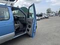 A blue 2010 Ford Econoline van with the driver's door open showcasing the interior seating and dashboard space