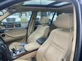 Interior of a 2009 BMW X5 featuring beige leather seats and a sleek dashboard design with a gear shifter and a tablet holder on the armrest