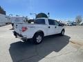 A white 2012 Ford F-150 pickup truck with a four-door configuration and a bed cover is parked on a paved surface