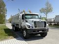 A 2009 International 7500 truck with a silver tank body and orange safety lights parked on a paved surface