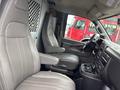 Interior view of a 2022 GMC Savana showing two leather seats steering wheel and dashboard with controls and cup holders