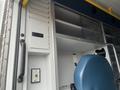 A 2016 Chevrolet Express with a blue driver's seat and storage compartments on the side panel.