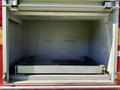 An empty compartment of a 2004 American LaFrance Eagle fire truck featuring a metal shelf with a textured surface