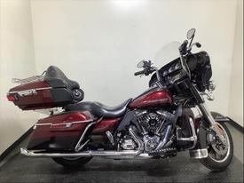 2015 Harley-Davidson Flhtk motorcycle in deep red with chrome accents and saddlebags featuring a large windshield and comfortable seat