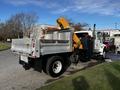 A 2013 International DuraStar 4300 truck with a metallic body and a yellow hydraulic arm attached at the rear