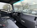 The interior of a 2015 Isuzu NPR HD with a driver's seat steering wheel and dashboard featuring various controls and gauges