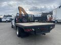 A 2017 Ford F-550 with a flatbed and a mounted crane on the back parked in a lot