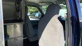 A 2013 Ford Econoline interior featuring a driver's seat and a partition with storage drawers visible