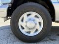 A close-up view of a silver wheel with a chrome hubcap mounted on a 2006 Ford Econoline tire branded Goodyear Wrangler