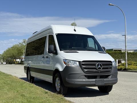 A 2023 Mercedes-Benz Sprinter van with a white exterior and gray accents parked on a street