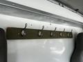 A row of metal hooks attached to a green wooden board mounted on the interior wall of a vehicle