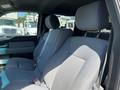 Interior view of a 2014 Ford F-150 featuring gray fabric seats with headrests and seatbelts in a spacious cabin setting