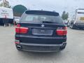 A black 2009 BMW X5 viewed from the rear with visible taillights and exhaust pipes
