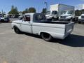 A 1962 Ford F-100 truck with a light gray body and modified rear wheel design, showcasing a classic style with a sleek appearance and single cab configuration
