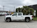 A white 2016 GMC Sierra 1500 pickup truck with chrome wheels parked on a concrete surface