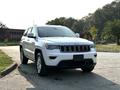 A 2020 Jeep Grand Cherokee in white with a distinctive grille and sleek body design parked on a paved surface