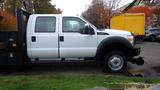 A white 2011 Ford F-550 truck with a crew cab and flatbed design parked on a gravel surface