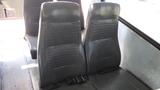 Two rows of dark leather seats inside a 2014 Freightliner Thomas Bus Diesel with a minimalist design and a metallic floor