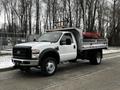 A 2008 Ford F-450 SD truck with a white cab and a flatbed trailer attached featuring red and silver detailing