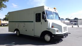 A 2004 Freightliner MT45 box truck with a white exterior featuring a green stripe six side access doors and a yellow beacon light on the roof