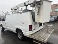 A white 2008 Ford Econoline van with a lift and a bucket at the top parked on a wet surface