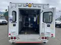 A 2014 Chevrolet Express ambulance with open back doors revealing interior seating and medical equipment layout