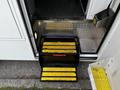 A 2013 Chevrolet Express with a fold-out step featuring yellow safety stripes extending from the entrance door
