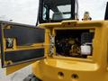 A yellow 2024 Caterpillar 306 excavator with an open engine compartment revealing internal engine components and a coolant reservoir