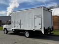 A 2013 Ford Econoline van with a white box truck body parked with a closed side door and no visible markings or graphics