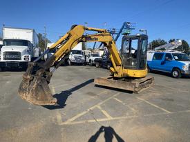 A yellow 2006 Komatsu PC55MR2 excavator with a bucket attachment prominently displayed in the foreground