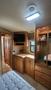Interior of a 2007 Winnebago Adventure featuring wooden cabinets a TV mount and closet space with hangers and drawers