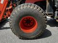 A large Goodyear tire from a 2011 Kubota M8540D tractor with a robust tread design and a vibrant orange wheel interior