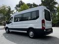 A 2022 Ford Transit van in white with a black trim parked at an angle showing its side and rear features large windows and a spacious interior