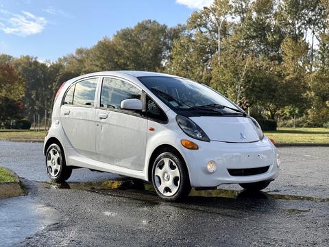 A 2012 Mitsubishi I-MiEV is parked with its compact design visible showcasing a white exterior and five-spoke alloy wheels
