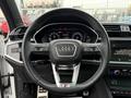 Interior view of a 2024 Audi Q3 featuring a stylish steering wheel with the Audi emblem and digital display panel behind it