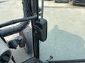 A black plastic door handle of a 2010 Kubota M6040 tractor with visible control levers and part of the tire in the foreground