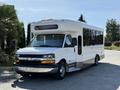 A white 2014 Chevrolet Express bus with a large front windshield and side windows designed for passenger transport featuring a sleek profile and chrome accents